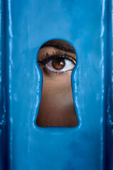 Female eye looking through a keyhole. 