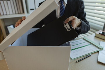 An office worker is putting important documents in boxes to prevent loss. A businessman is putting...