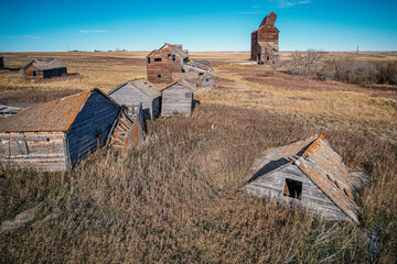 A desolate landscape with a few old buildings and a large barn