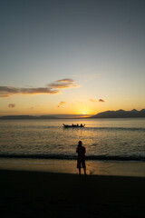 Fototapeta premium a man is walking on the beach at sunrise