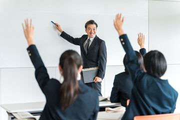 学校の授業・塾で先生・講師・教師から指導を受ける小学生・中学生・高校生・女子高生 