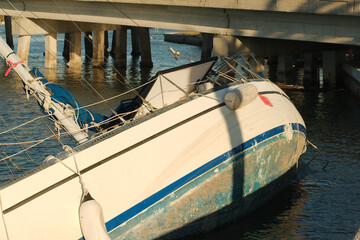 Wide view Derelict boat on the edge of the concrete Seawall on Boca Ciega Bay in St Pete Beach FL. Blue Sky and calm water. 
