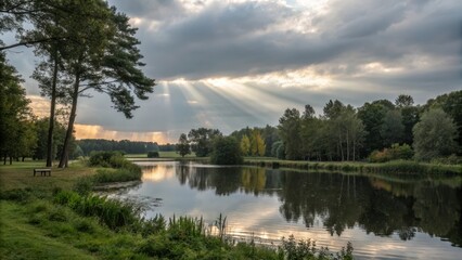 Serene lakeside scene with sun rays piercing through dramatic clouds, reflecting on calm water, and a lone bench by a tree.