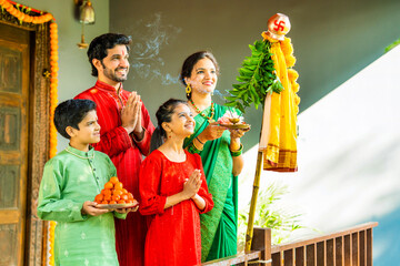 Happy Indian family in ethnic attire performing Gudi Padwa puja, a Hindu New Year celebration
