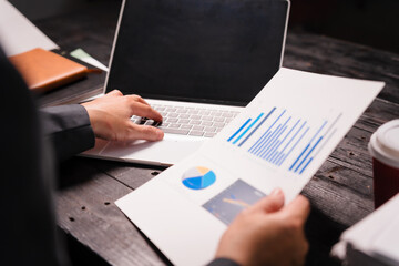 A young Asian man in a formal suit works late at night at his desk, analyzing stock market charts...