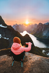 Woman drinking coffee on Reinebringen mountain top traveling in Norway hiking outdoor, girl sitting...