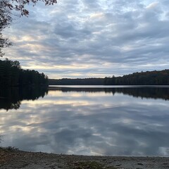 Fototapeta premium Tranquil Lake at Dusk Reflecting an Autumn Sky with Colorful Trees and Peaceful Water Surface in a Serene Outdoor Landscape
