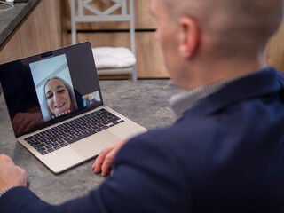 Businessman using laptop for video conference with colleagues while working remotely from home office. Embracing technology for seamless communication and collaboration in modern business environment