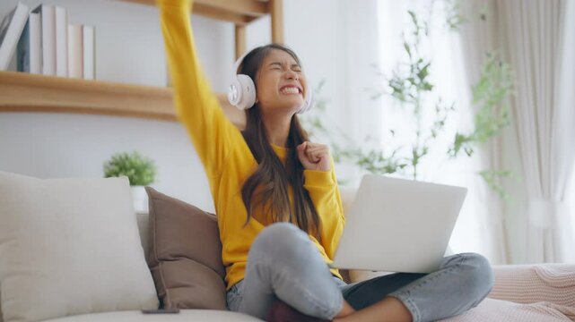 Funny euphoric young asian woman celebrating winning or getting ecommerce shopping offer on computer laptop. Excited happy girl winner looking at notebook celebrating success