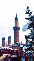 Obraz premium Erzurum Ulu Mosque and the historic Twin Minaret Madrasa framed snow and trees.