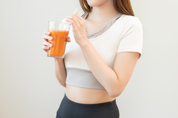 Orange detox juice, asian young woman hand holding a glass of vegetable juice, carrot smoothie for diet, drinking healthy meal food for weight loss on background. Lifestyle, vegan nutrition.