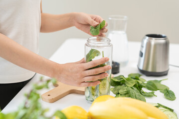 Vegetable smoothie detox, woman hand making healthy raw fresh green fruit juice with blender machine, preparing drink with spinach in kitchen at home, eating vegan diet. Healthy dieting, weight loss.