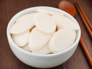 도자기 그릇에 담긴 떡국떡과 숟가락, 젓가락