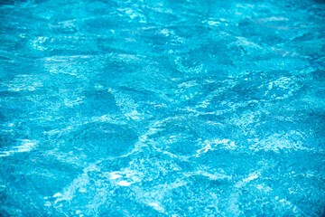 Blue pool water background. Blurred transparent clear calm water surface texture. Water waves in sunlight with copy space.