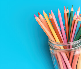 Fototapeta premium Colorful pencils in glass jar against bright blue background