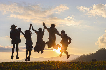 Silhouette group of happy children jumping playing on mountain at sunset, summer time