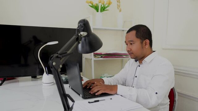 Close-up of a freelance developer's hands typing program code on a laptop keyboard in the office. A businessman works in the office. A scriptwriter writes text on a computer keyboard.