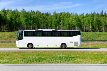 White coach bus at speed on motorway on a sunny day of summer, side view, copy space for your text.