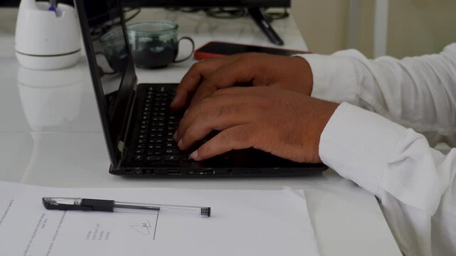 Close-up of a freelance developer's hands typing program code on a laptop keyboard in the office. A businessman works in the office. A scriptwriter writes text on a computer keyboard.
