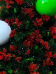 Festive Christmas decoration featuring Pohutukawa tree foliage and red blossoms, adorned with shiny green and white ornaments.