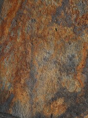 Close-up of a rusty, weathered stone wall with various patches and spots, offering a rich, earthy texture and natural aesthetic