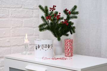Festive and Cheerful Winter Decor Featuring a Candle Surrounded by Greenery on a White Table