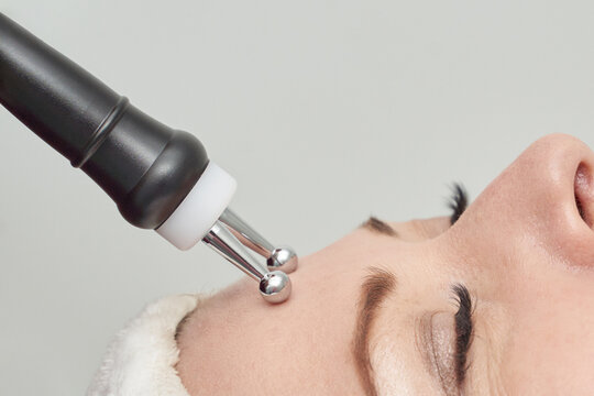 Close up of microcurrent facial treatment on caucasian female young adult with electrotherapy device.