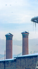 Twin Minaret Madrasa of Erzurum under a serene winter sky with icy details.