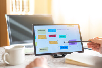 Fototapeta premium Person Or Entrepreneur Planning Appointments And Calendar Dates.Successful Person Organizing Their Weekly Schedule For Client Appointments,Business Calls And Events In The Office Using A Tablet
