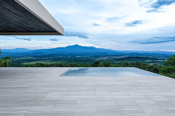Fototapeta premium Tranquil modern patio with infinity pool overlooking scenic mountains at dusk