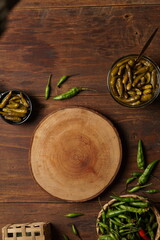 Sweet and sour green chili pickles with brown wood background