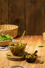 Sweet and sour green chili pickles with brown wood background