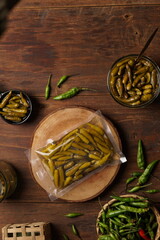 Sweet and sour green chili pickles with brown wood background