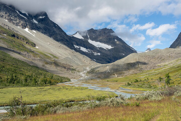 Glacial river flowing in the mountain valley on a sunny summer day. Storfjord, Steindalen, Lyngen Alps, Norway