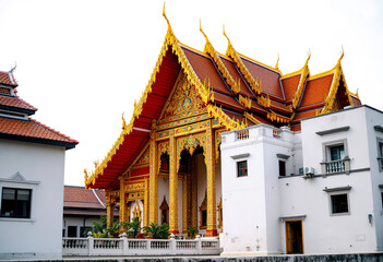 A Thai Buddhist temple with ornate red and gold architecture, including a large roof with intricate designs and multiple levels (4)