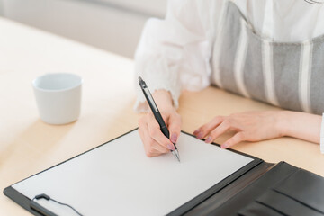 契約書・同意書にサインする主婦・女性の手元
