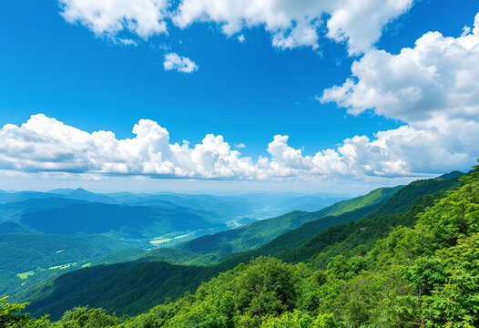 A scenic view of a mountainous landscape with lush green forests and rolling hills under a blue sky with fluffy white clouds