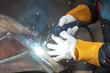 Industrial worker welding metal with sparks flying in workshop