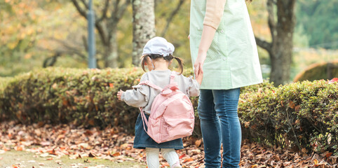 秋の公園を散歩・遠足する保育士の女性と園児（保育園・幼稚園保母）
