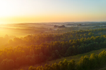 Misty sunrise over rural fields with golden light