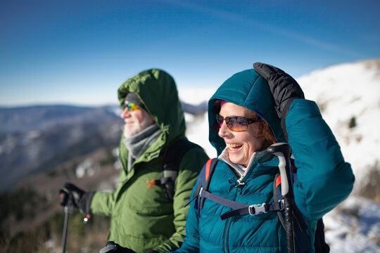 Portrait of active seniors enjoying nature. Romantic winter hike for an elderly couple in snowy mountains.