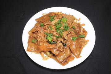 Delicious dish on white plate. A plate of delicious food on a black background