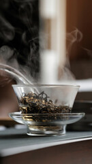A steaming teacup filled with loose leaf tea is beautifully displayed in a clear glass bowl