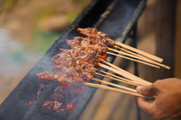 A plate of meat is on a grill with a lot of smoke. The meat is cooked and has a lot of sauce on it
