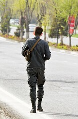 Military man in uniform walking on the road