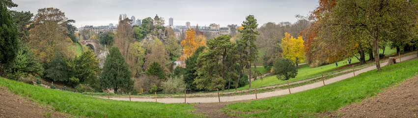 Paris, France - 11 16 2024: Park Buttes Chaumont. Panoramic view of remarkable trees and vegetation with fall colors.