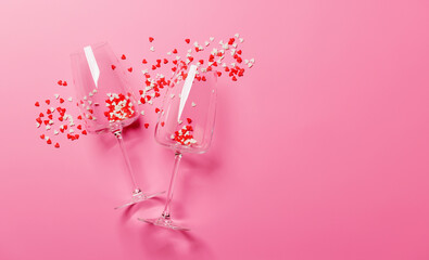 A champagne glasses adorned with heart-shaped decor on a vibrant pink background