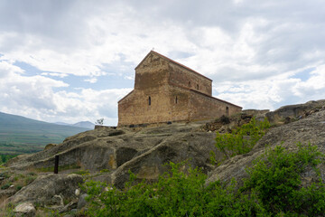 Fototapeta premium A church with a tiled roof on a hill in an ancient city. Uplistsikhe is an ancient rock-hewn town.