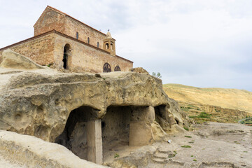 Church with a tiled roof on a hill in an ancient city. Ruins of old caves. Uplistsikhe is an ancient rock-hewn town.