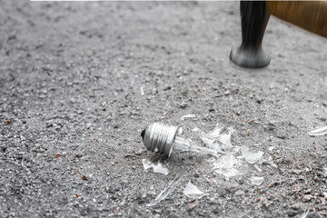 Obraz premium Closeup photo of incandescent lamp broken into fragments with hammer, an incandescent lamp being broken by a hammer, glass pieces mid-air